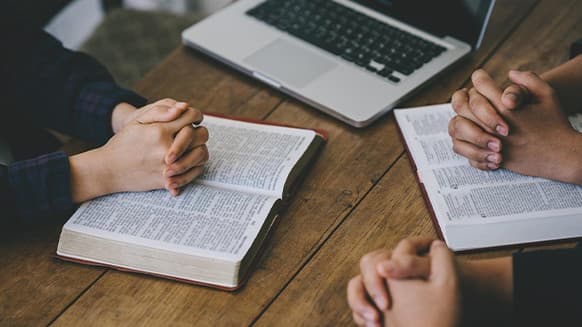 Several people with bibles and folded hands